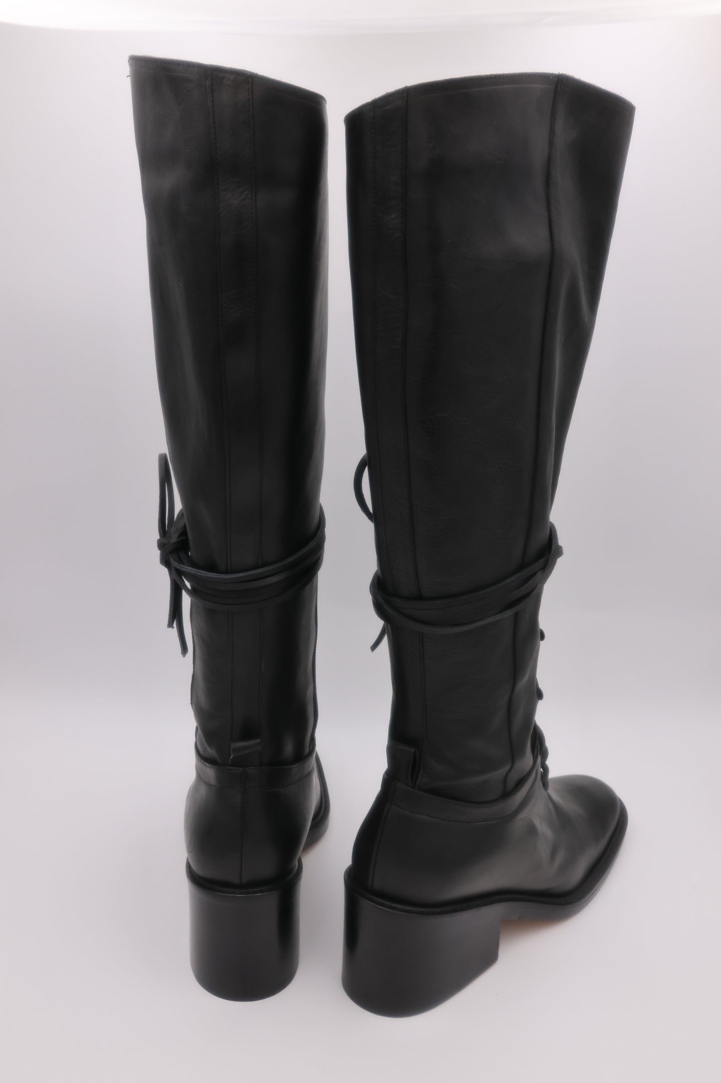 Black knee-high boots with chunky heels on a white background