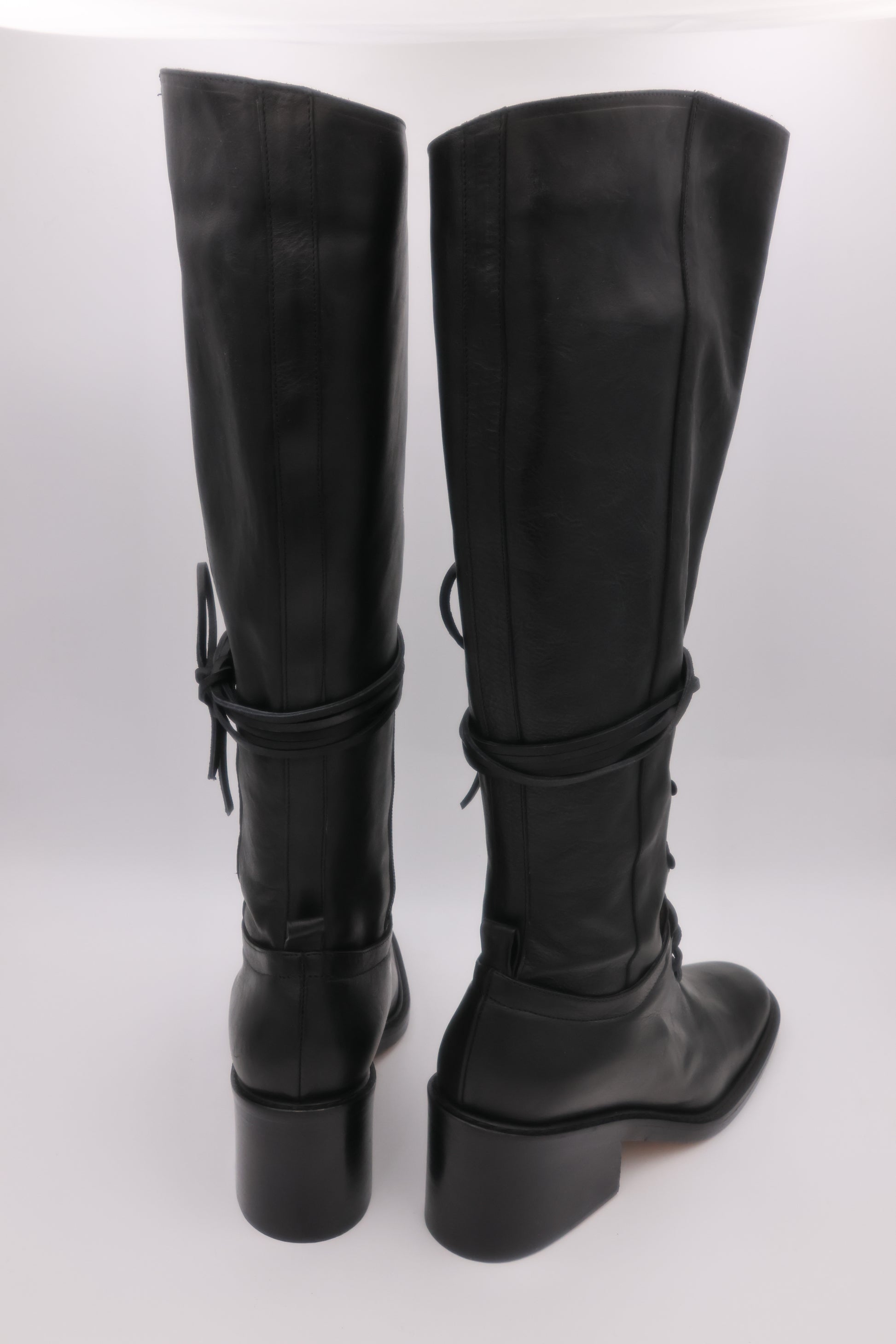 Black knee-high boots with chunky heels on a white background