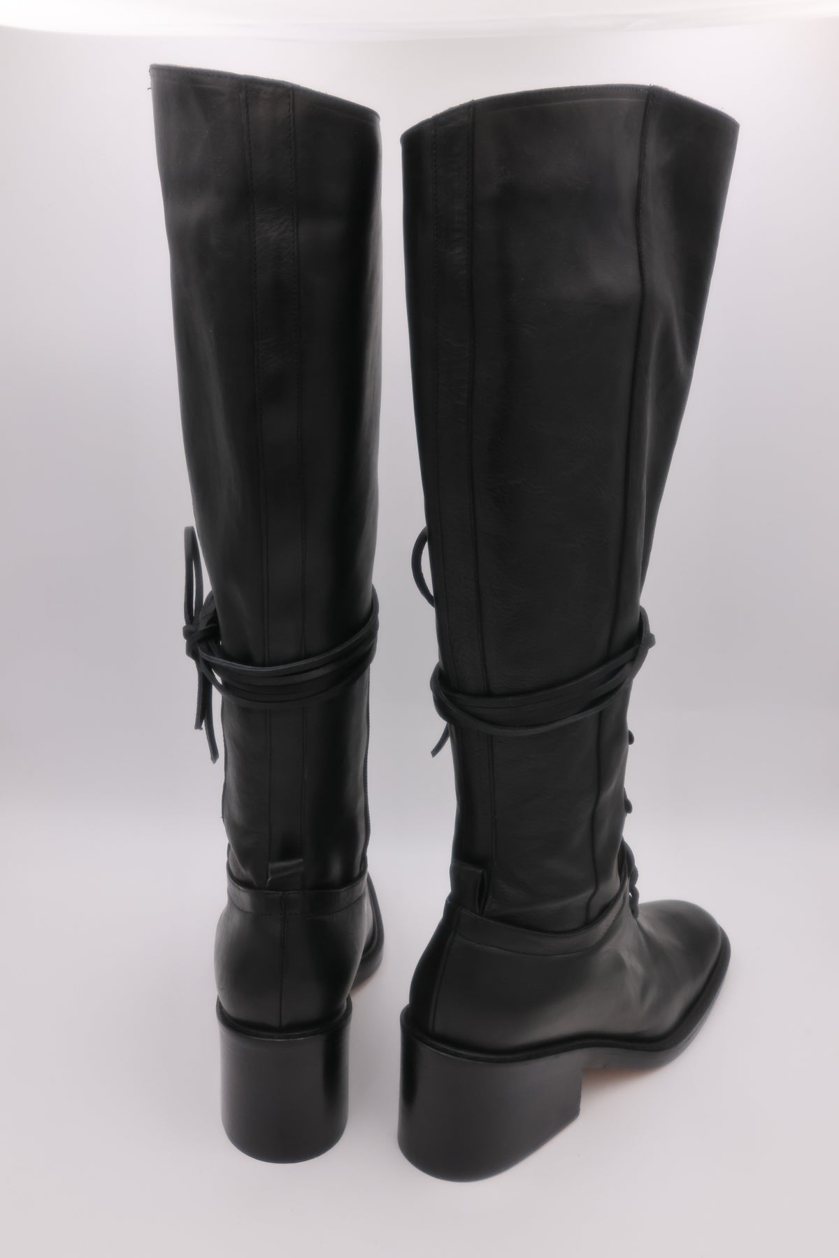 Black knee-high boots with chunky heels on a white background