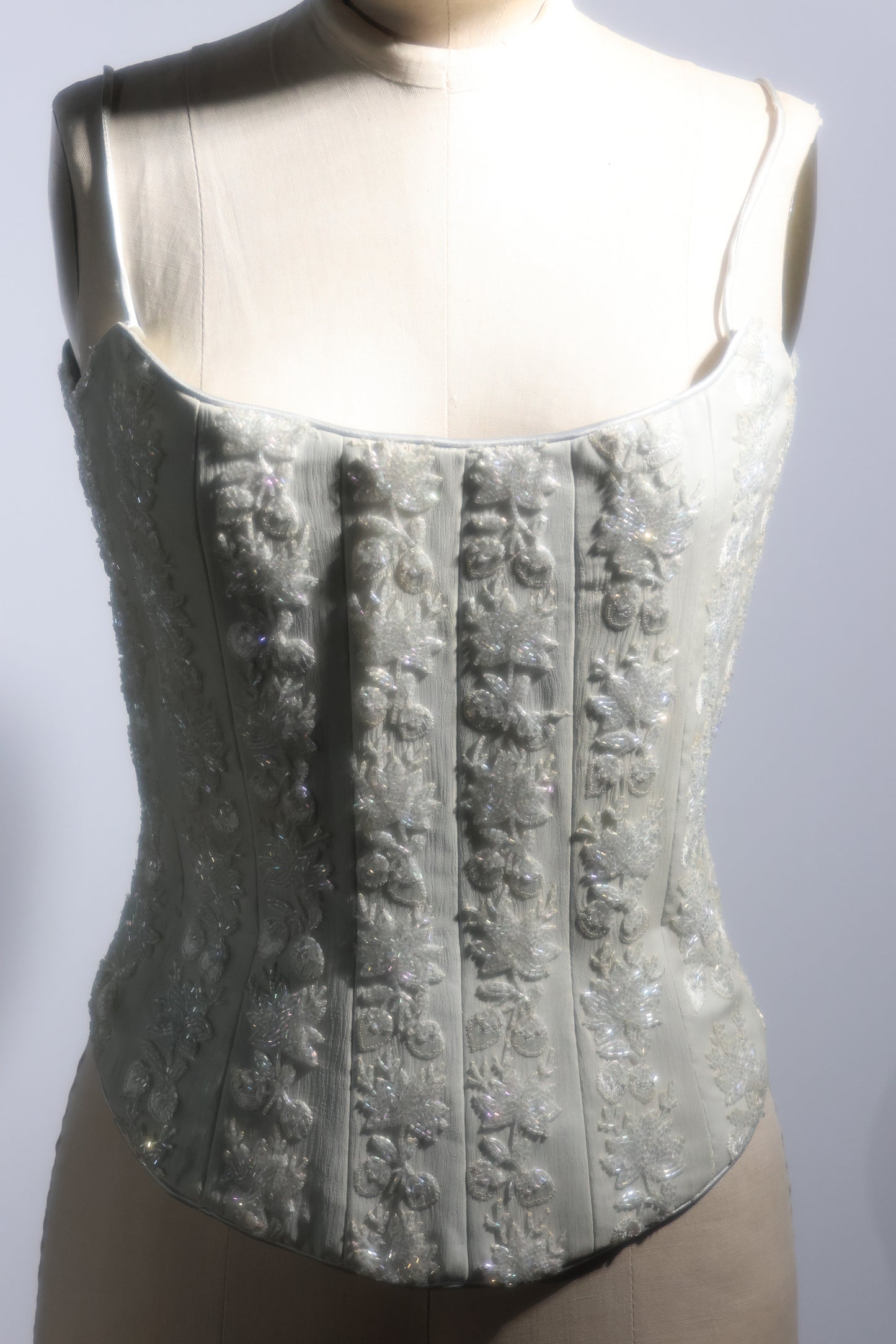 Silver corset on a mannequin against a plain background