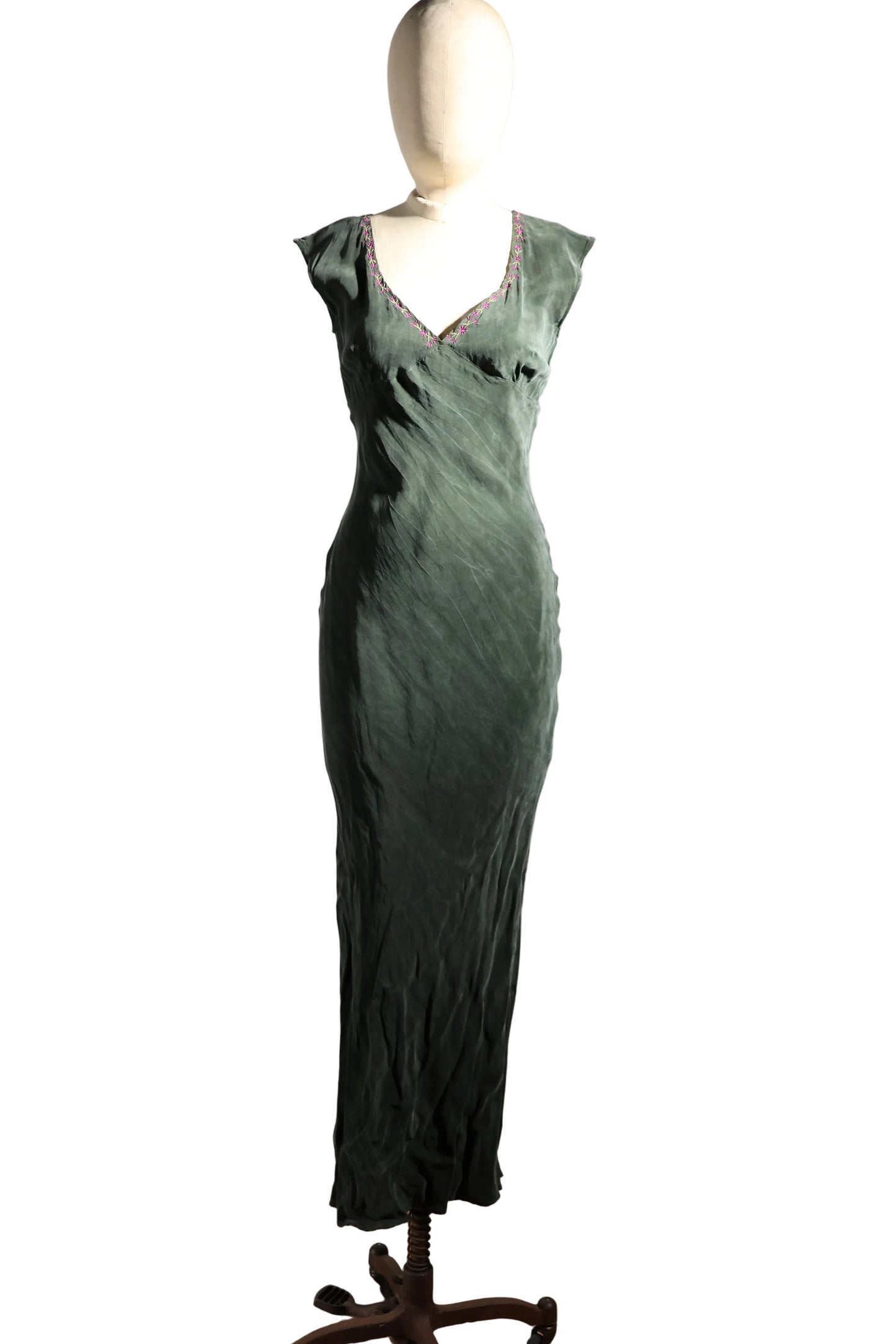 Green evening gown on a mannequin against a plain background