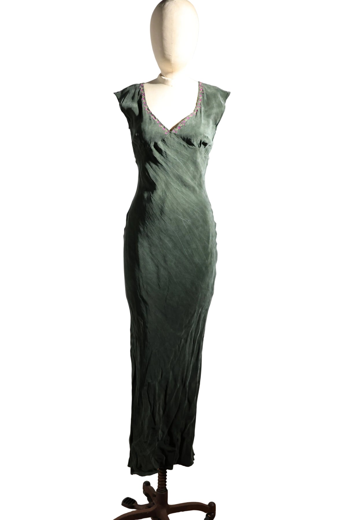 Green evening gown on a mannequin against a plain background