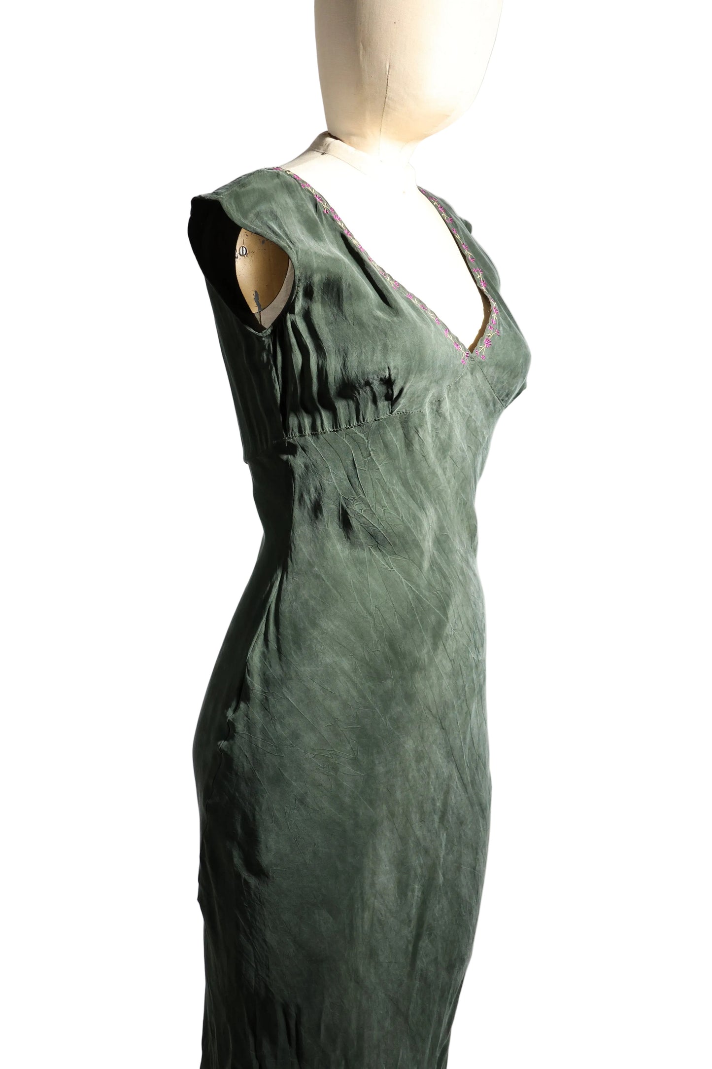 Green dress on a mannequin against a plain background