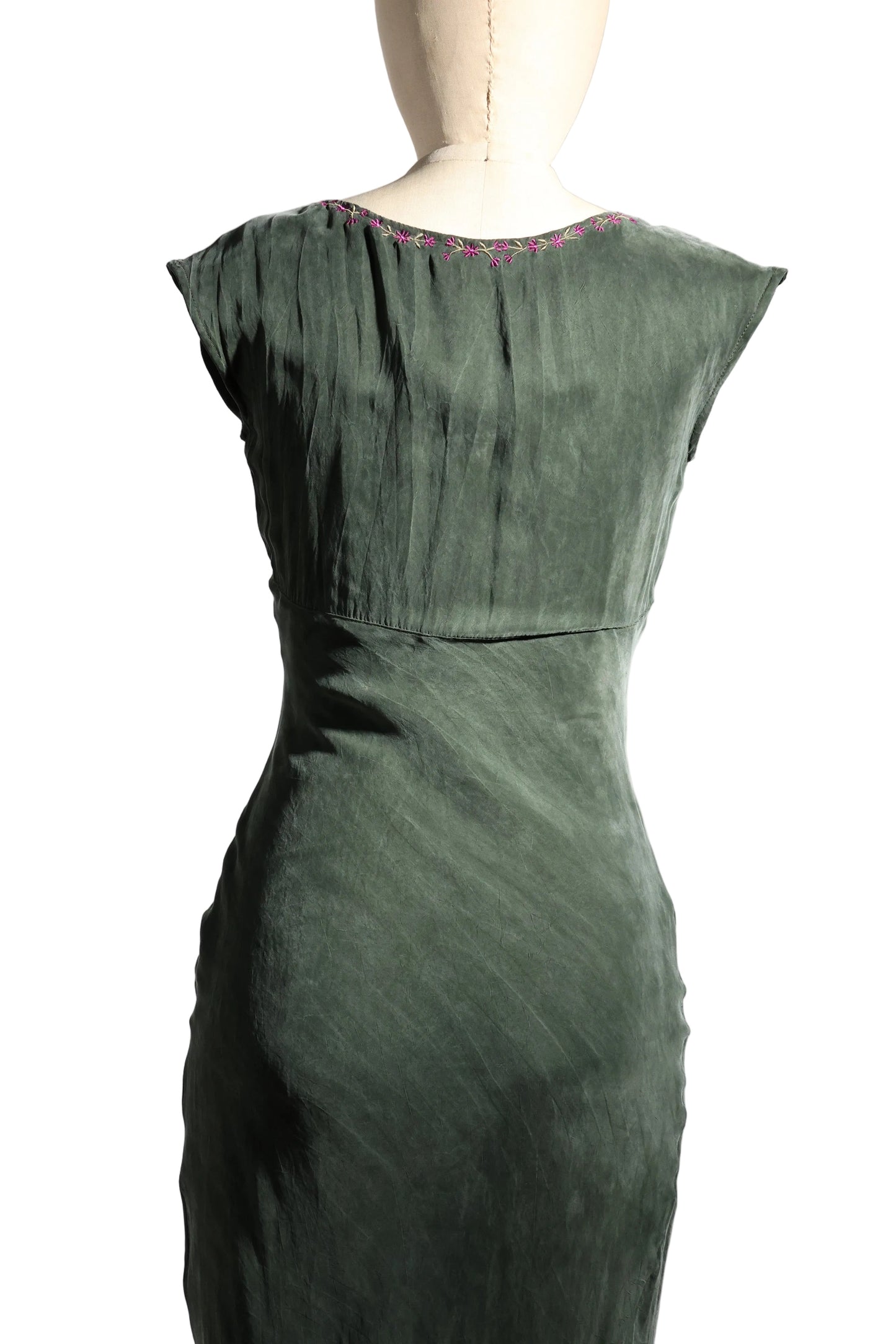 Green dress on a mannequin against a plain background