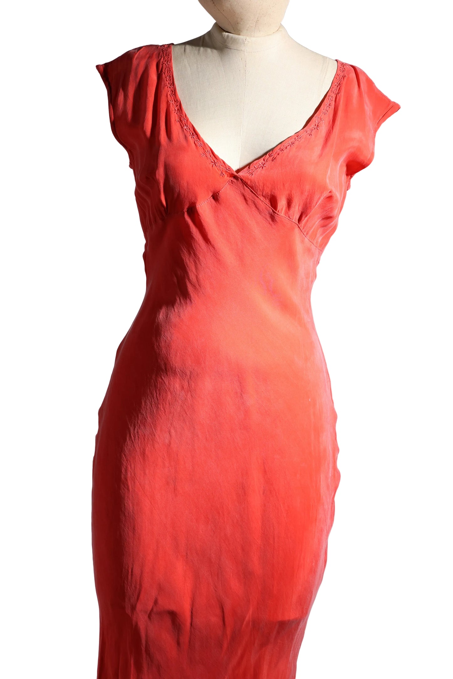Red evening gown on a mannequin against a plain background