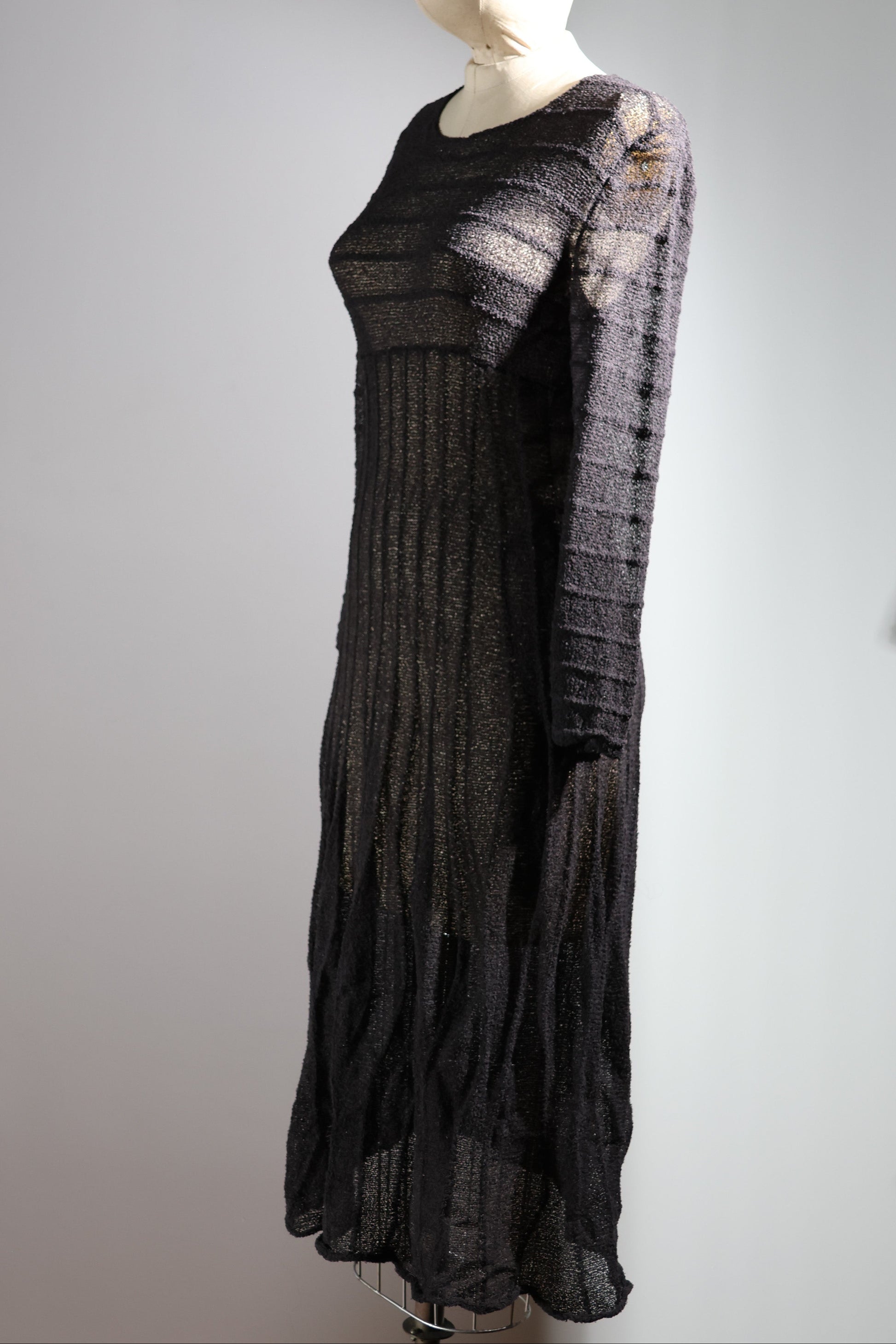 Black textured dress on a mannequin against a plain background