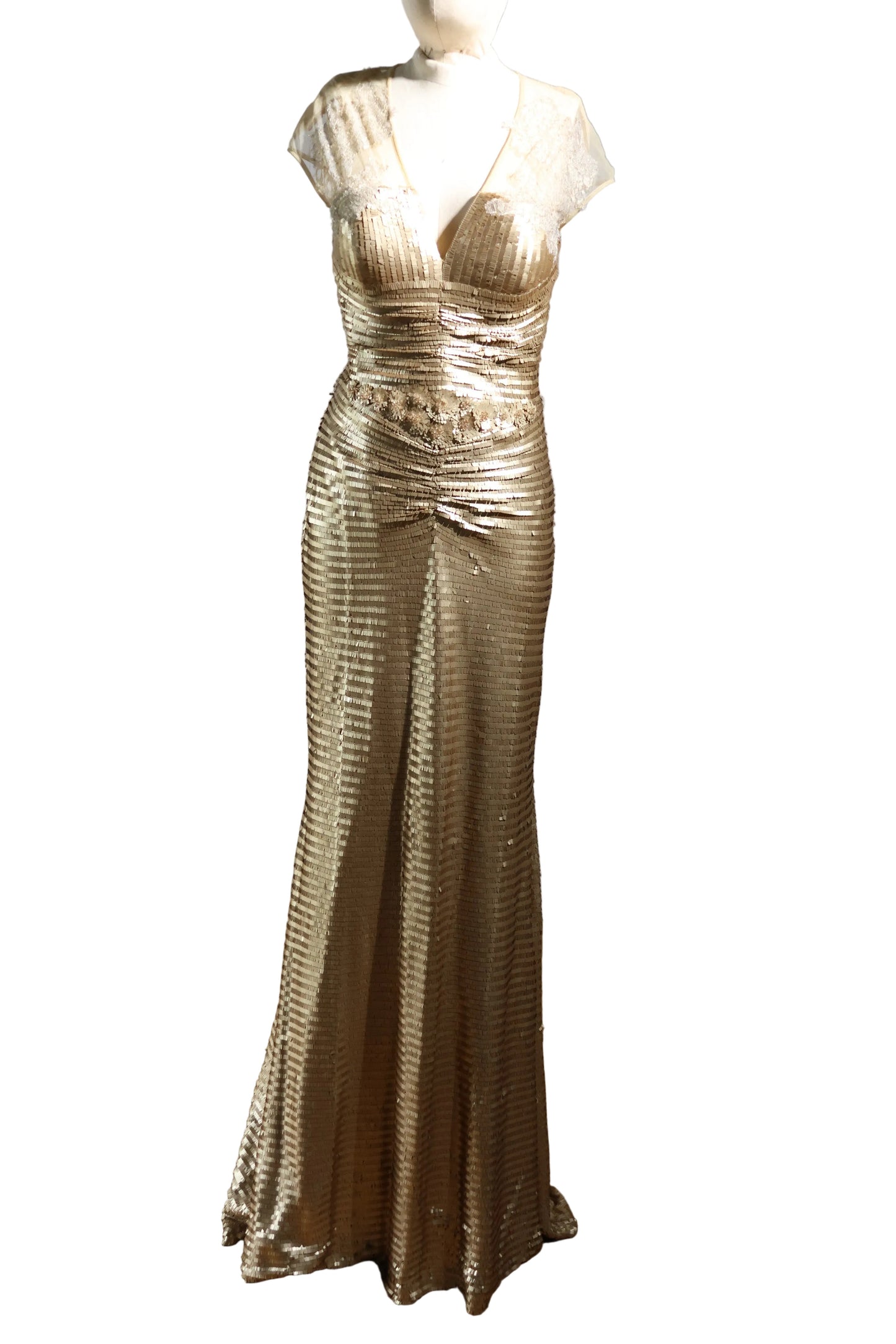 Gold evening gown on a mannequin against a plain background