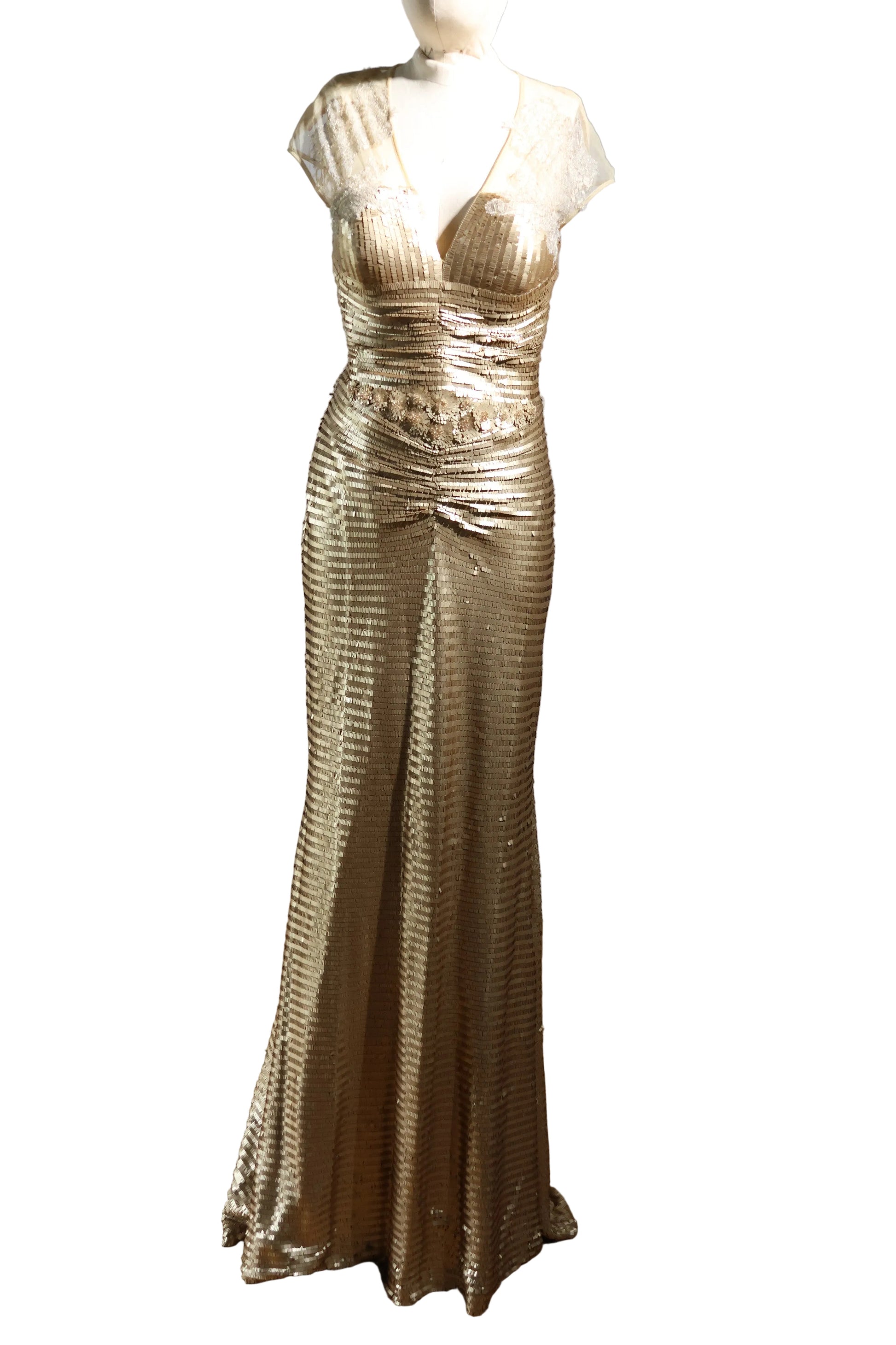 Gold evening gown on a mannequin against a plain background