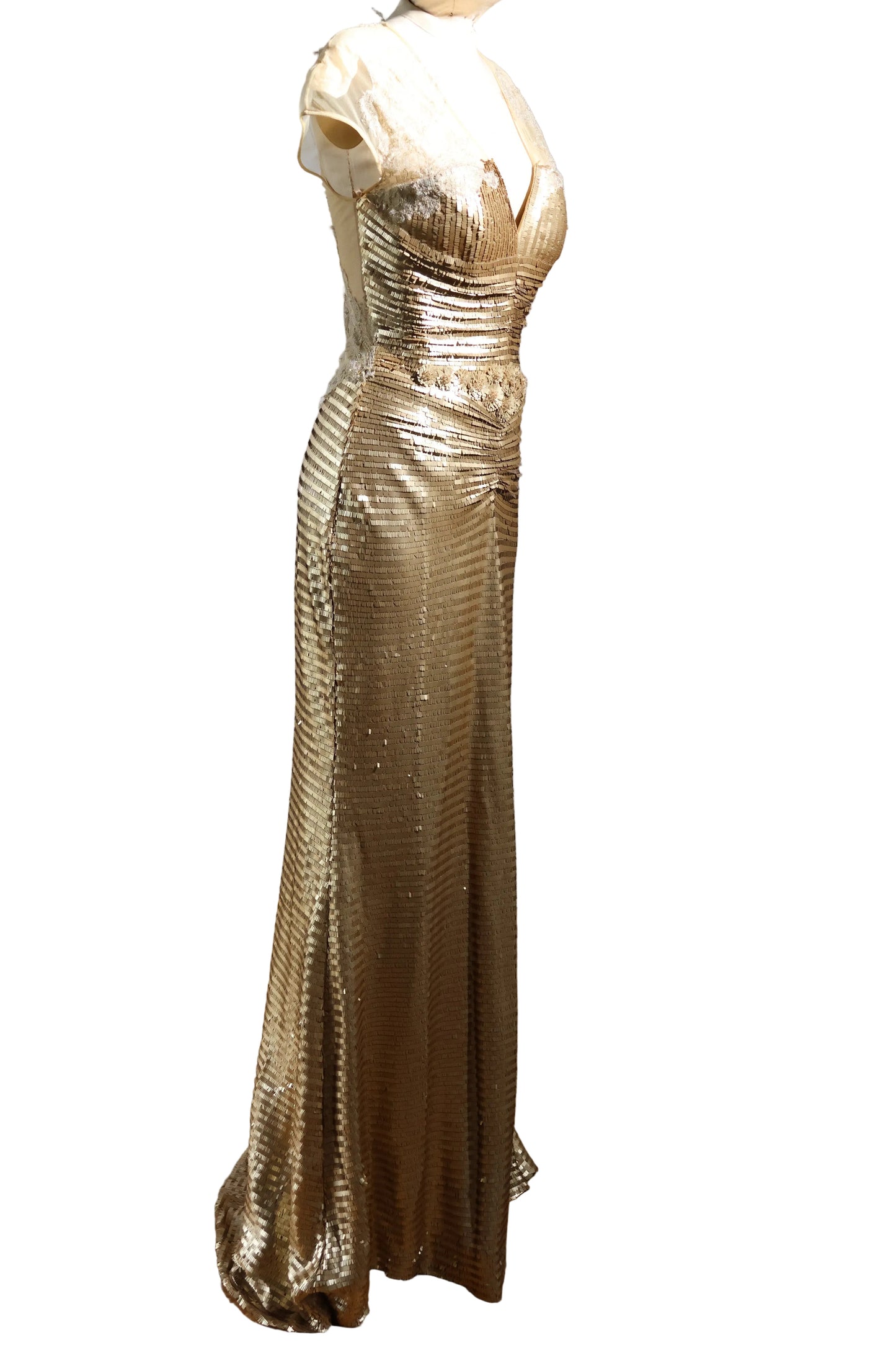 Gold evening gown on a mannequin against a plain background