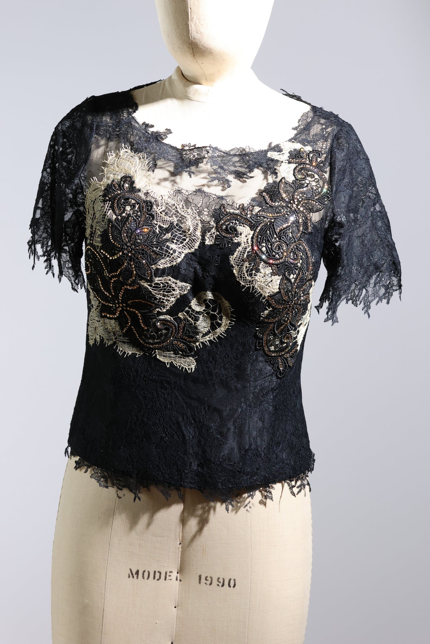 Black lace top on a mannequin with a plain background