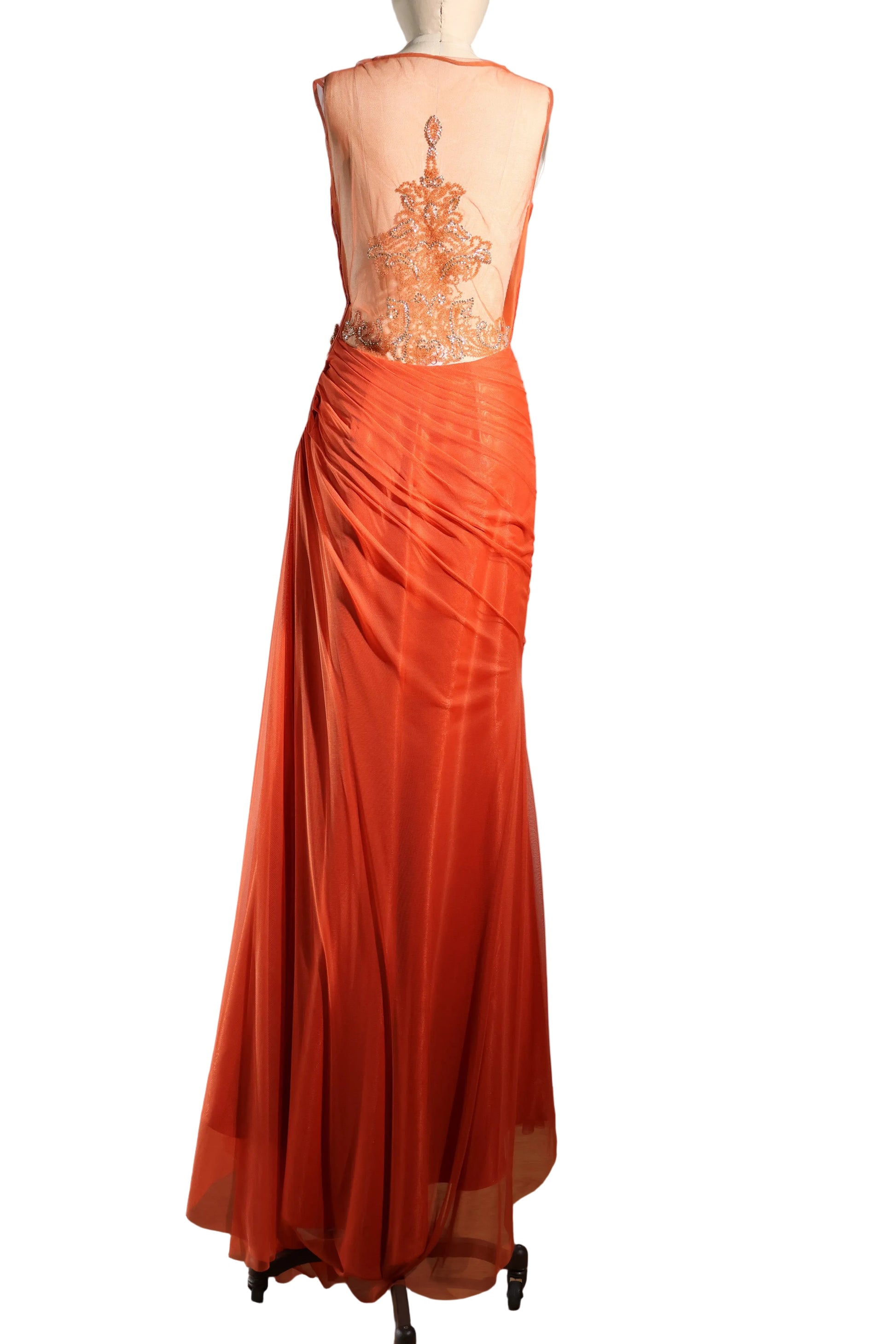 Orange evening gown with intricate back design on a mannequin against a plain background