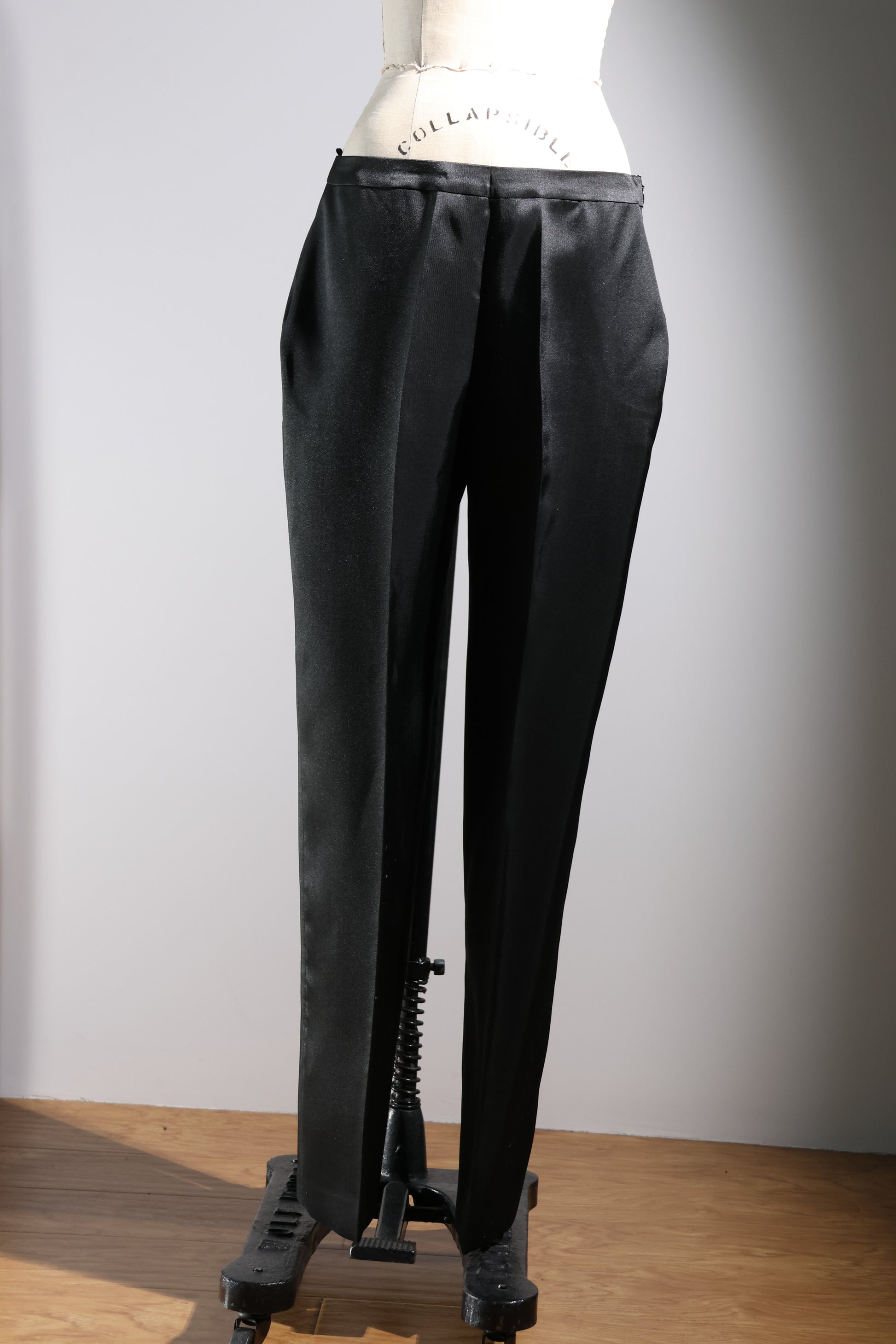 Black silk pants on a mannequin against a plain background