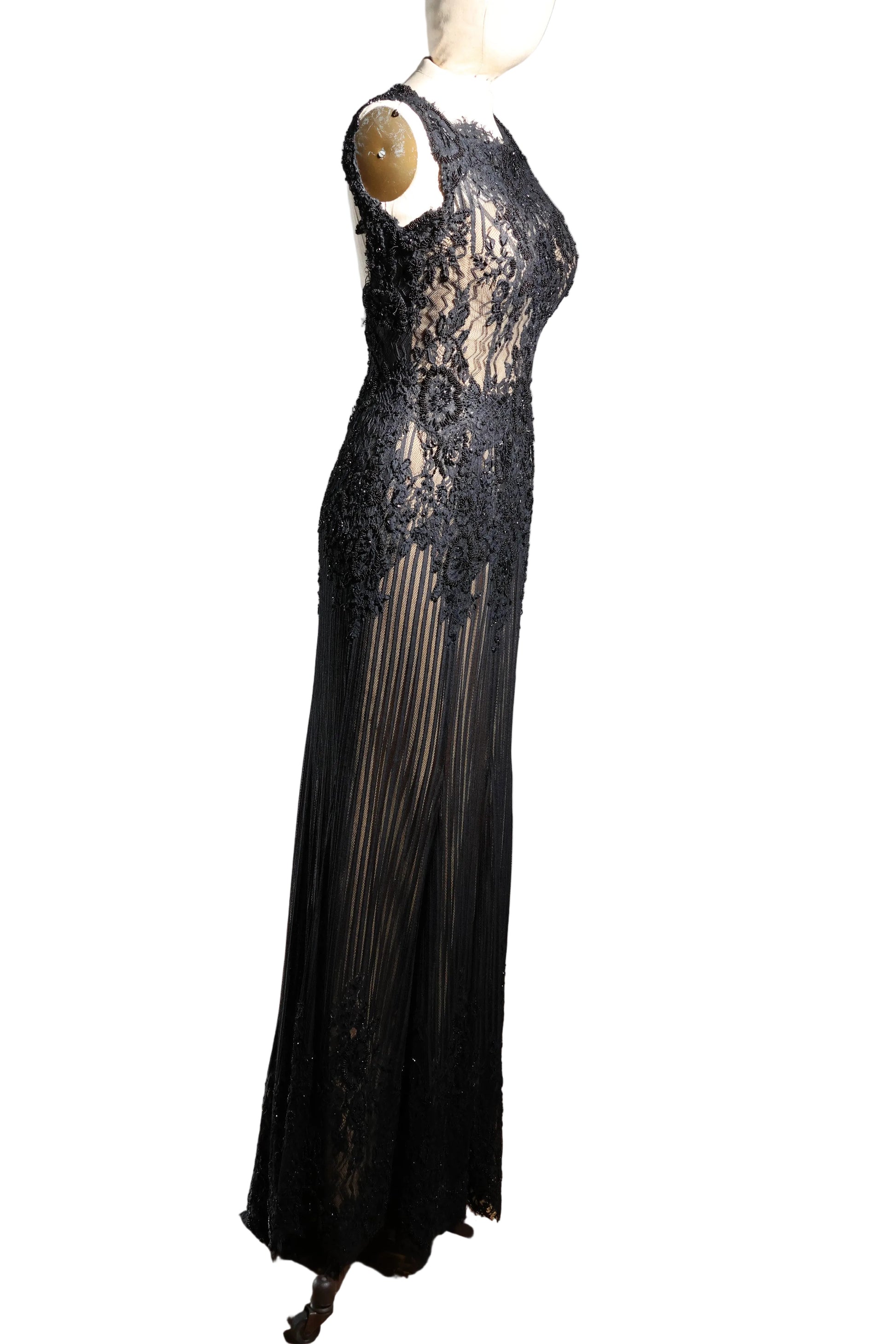 Black lace evening gown on a mannequin against a plain wall.