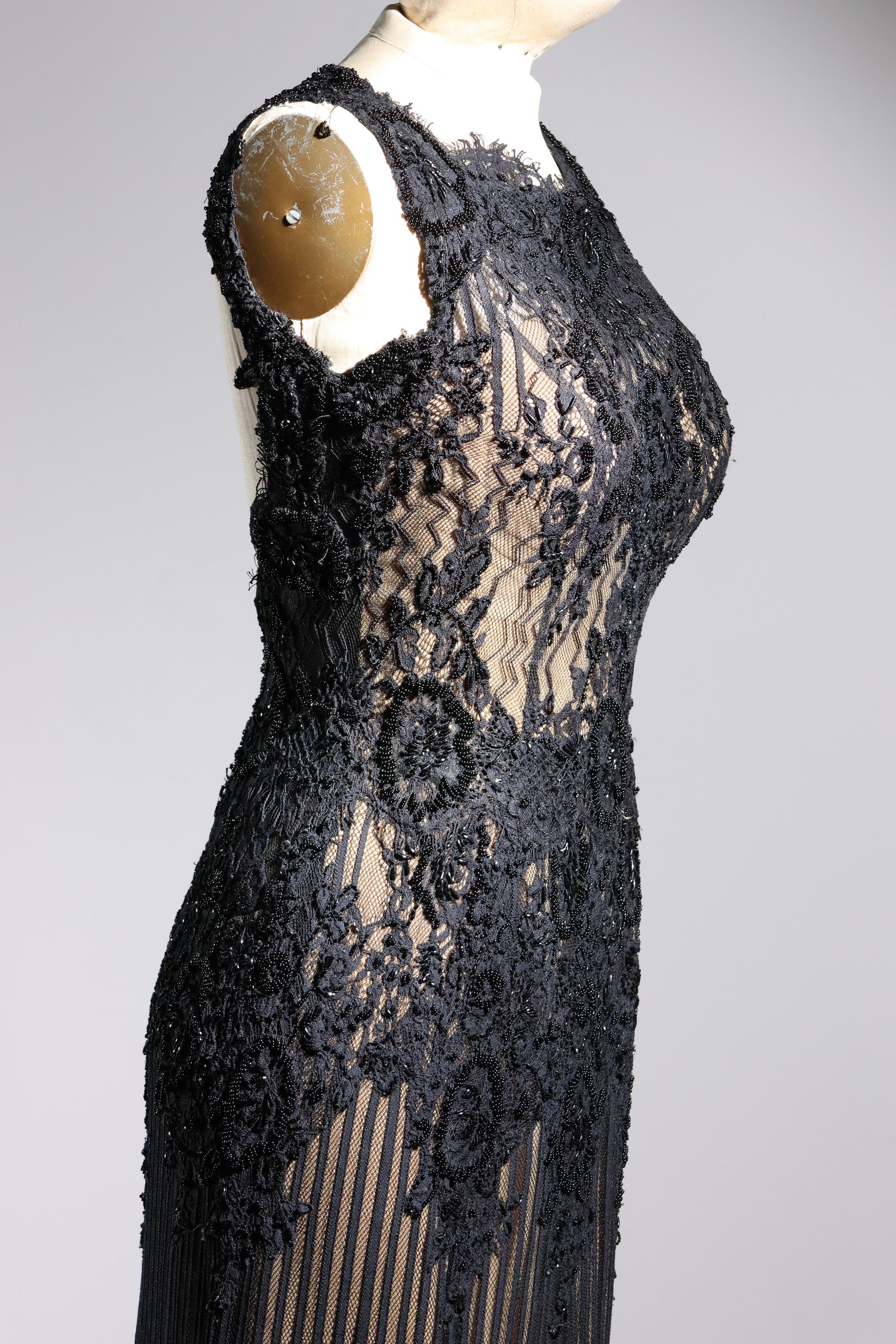 Black lace dress on a mannequin against a gray background
