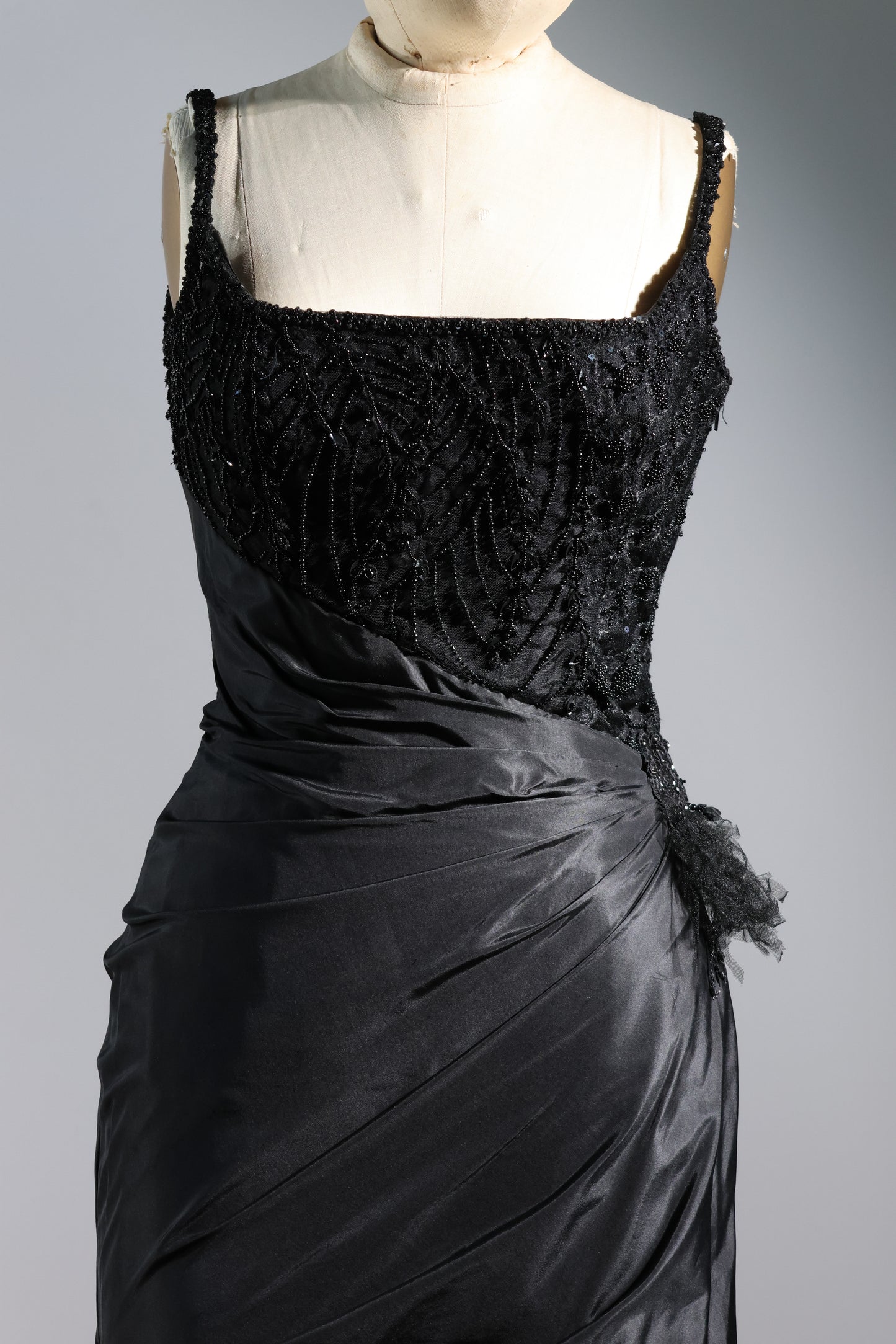 Black evening gown on a mannequin against a gray background