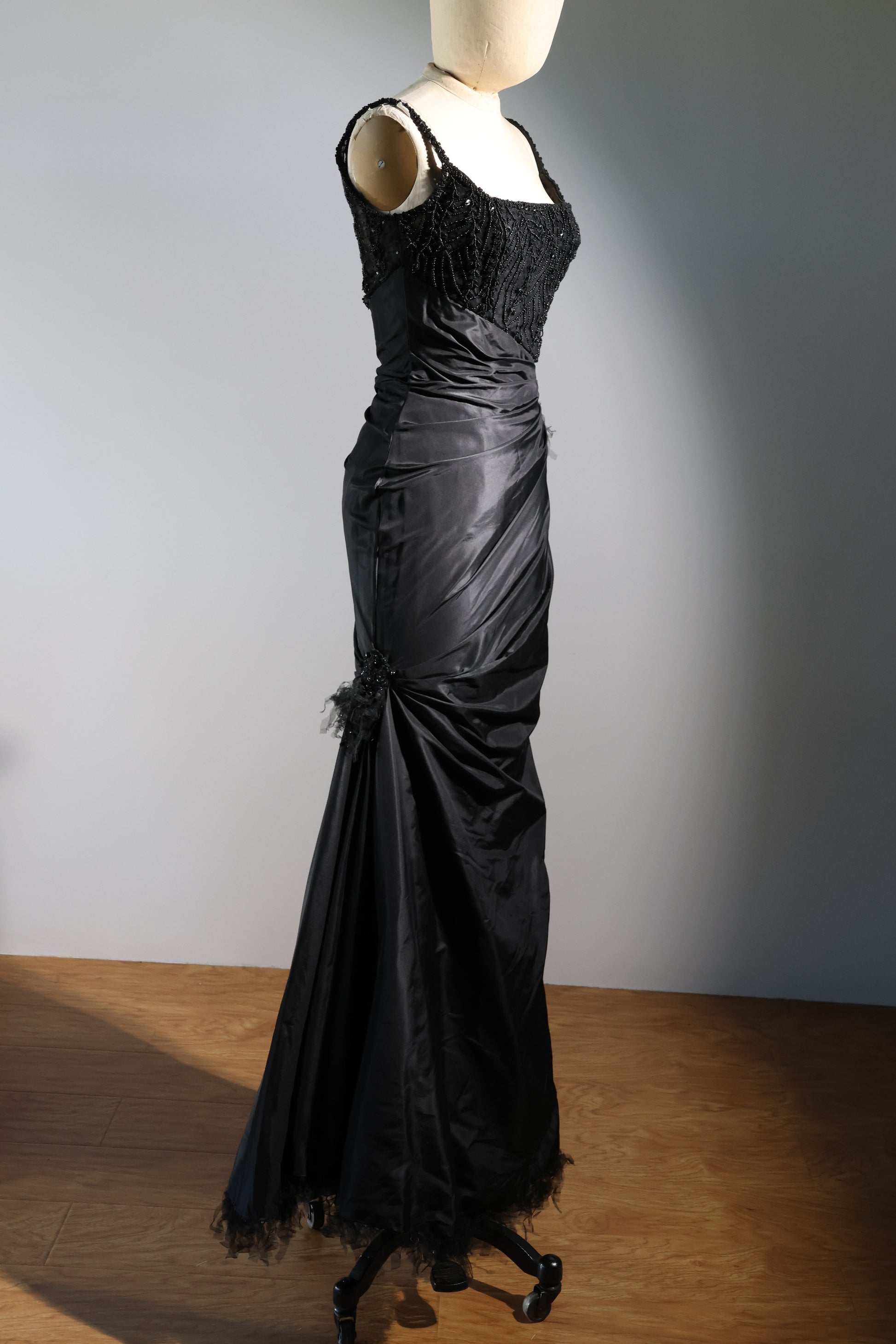Black evening gown on a mannequin against a plain background