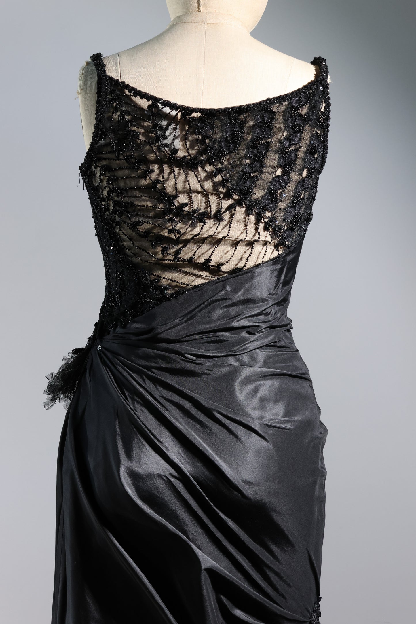 Black lace top and satin skirt on a mannequin against a gray background