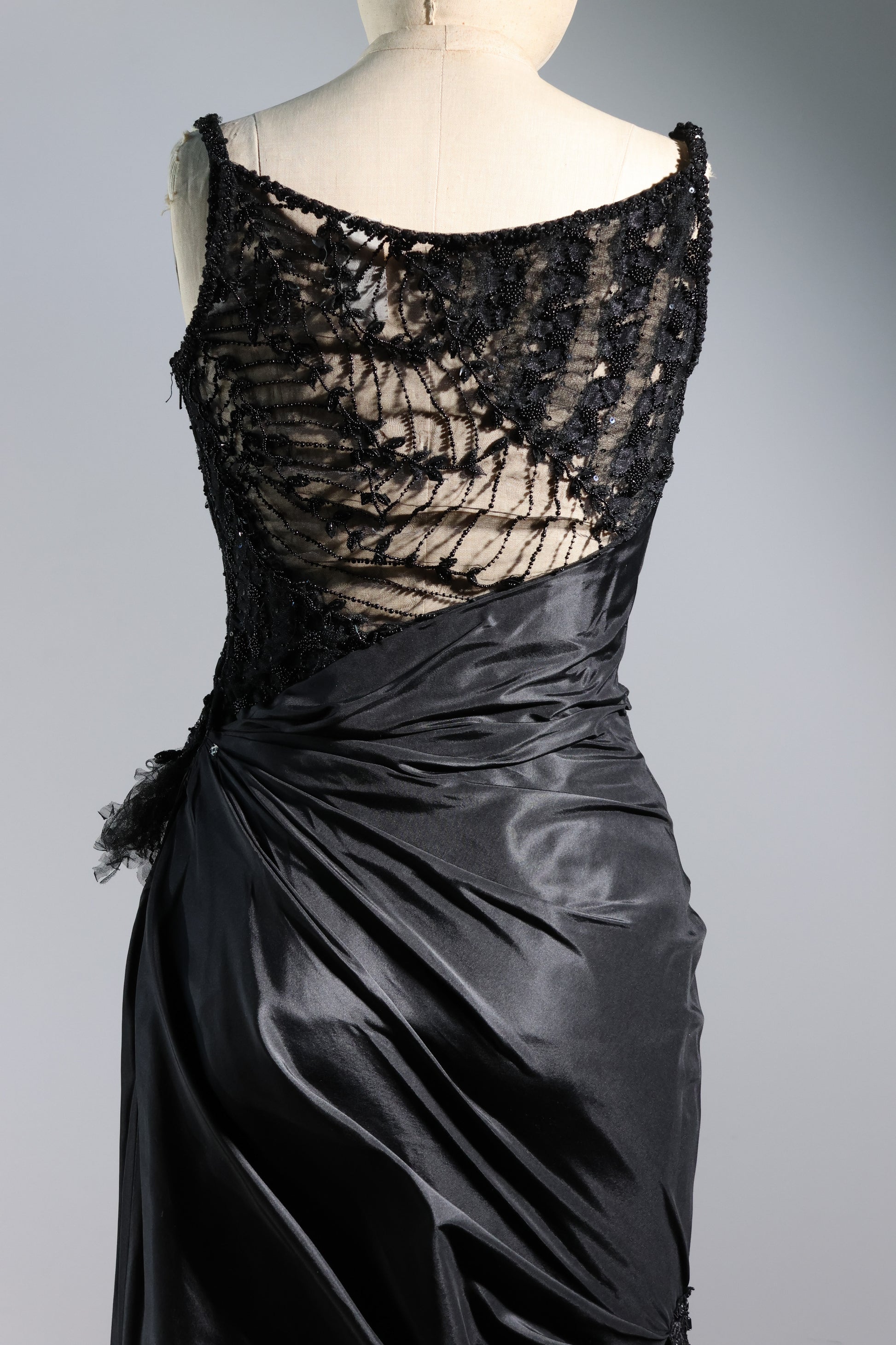 Black lace top and satin skirt on a mannequin against a gray background