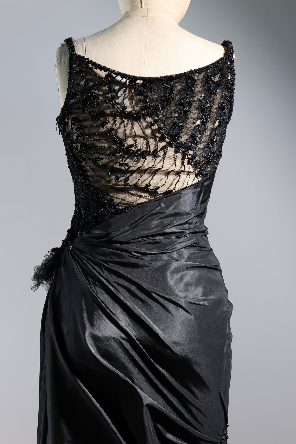 Black lace top and satin skirt on a mannequin against a gray background