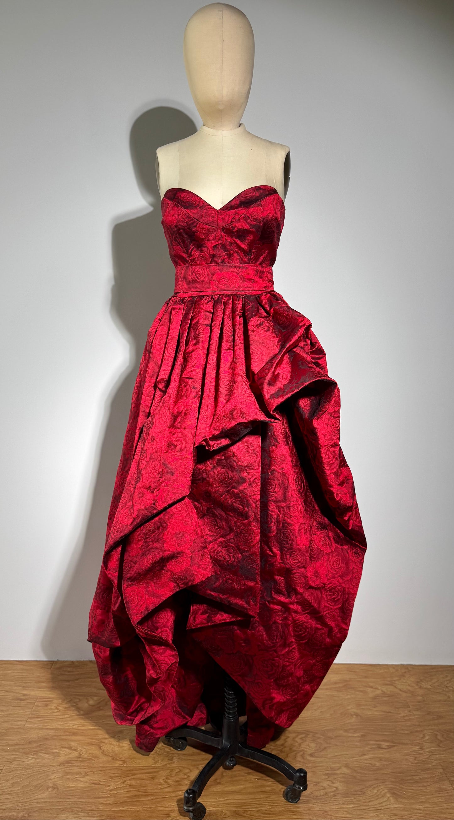 Red strapless gown on a mannequin against a plain background